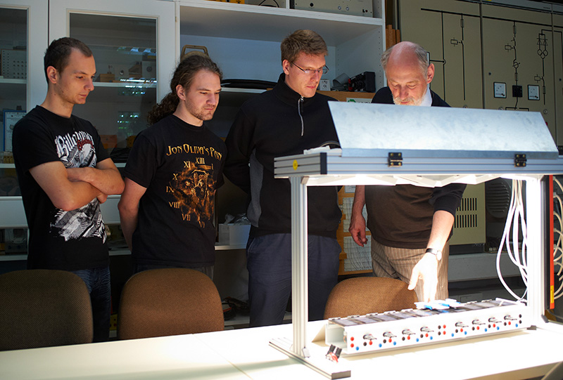 Ein Professor erklärt drei Studenten das Prinzip von Solarzellen.